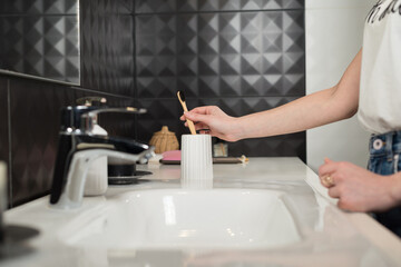 Closeup female hand is holding ecological bamboo brush. woman is preparing going to clean teeth. Tool for oral care. Personal hygiene product concept