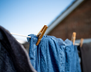Close and selective focus on a wooden clothes peg keeping a pair of blue denim pants or jeans on a...