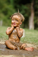 Criança brincando na lama linda com sorriso perfeito.
