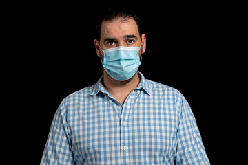 Portrait of bearded man dressed in white and blue plaid shirt posing worried isolated on black studio background