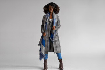 Female black model wear grey plaid coat with scarf with a trendy afro hairstyle isoalted on gray - 428863000