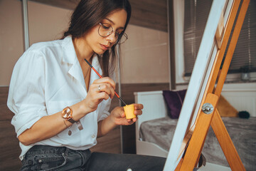 Beautiful talented female artist painting at her home.