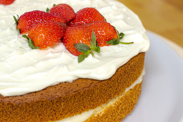 Cream tart with strawberries and lemon sponge cake on white plate