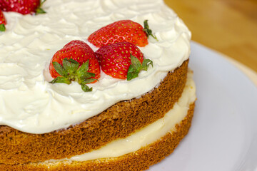 Cream tart with strawberries and lemon sponge cake on white plate