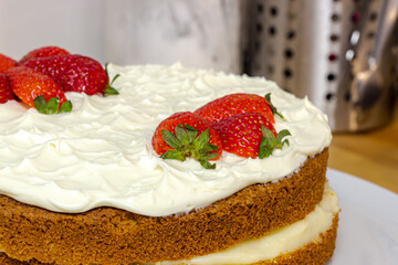 Cream tart with strawberries and lemon sponge cake on white plate