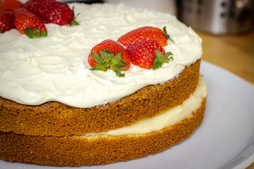 Cream tart with strawberries and lemon sponge cake on white plate