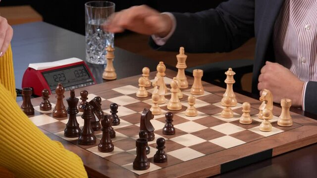 Two unrecognizable people play chess game and one is castling the king.