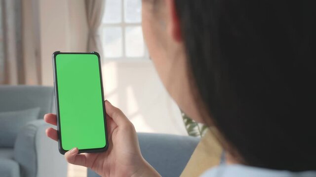 Female Using Smartphone With Green Screen In Living Room 
