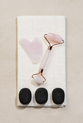 Beauty Products scraper gua sha , roller in rose quartz and Zen Stones. Flat lay, top view.