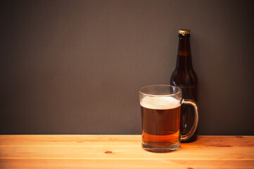 Mug and bottle with beer on wooden table.