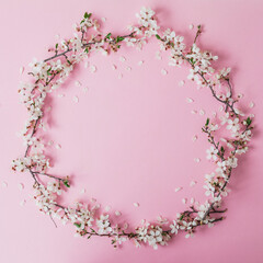 Round frame of spring flowers isolated on pink background. Flat lay, top view. Spring background.