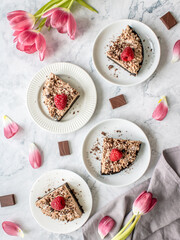 Overhead shot of delicious chocolate cake with raspberries and flowers on white background. Top view, flat lay.