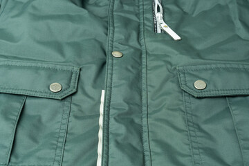 Fragment of a green jacket made of waterproof fabric with high-quality seams, pockets, metal...