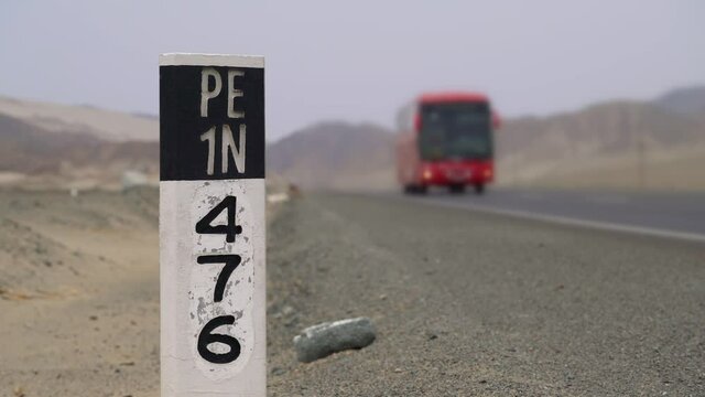 Panamericana road in Peru with a pylon with the highway number PE1N and a bus in the background, South America. PERU