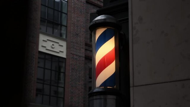 Barbershop light barber lamp in the city center. Motion of barbershop pole spinning at barber shop. Barbershop pole on the outside building wall.