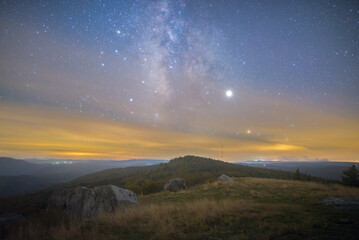 The Milky Way galaxy core rising over a mountainous landscape in West Virginia