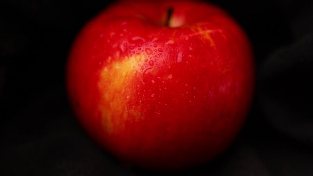 Red apple with water drops on black background