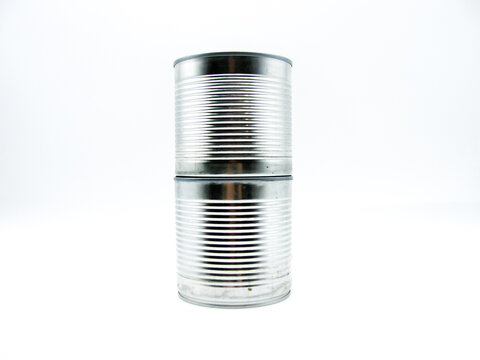 Two closed tin cans stand on top of each other on a white background
