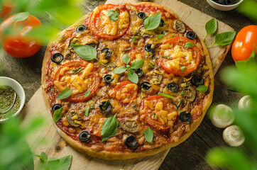 Vegetarian pizza with cheese, mushrooms and olives on wooden background with selective focus