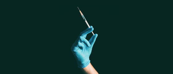 Coronavirus vaccine syringe held by doctor or nurse in blue medical ppe glove against black...