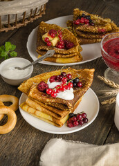 Pancakes with berries, sour cream for the Russian Maslenitsa holiday on a wooden background