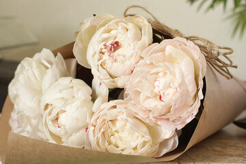 Bouquet of delicate pink peonies in craft paper