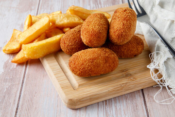 Naklejka premium Homemade croquettes with chips on wood cutting board