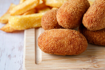 Homemade croquettes with chips on wood cutting board