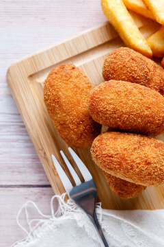 Homemade croquettes with chips on wood cutting board