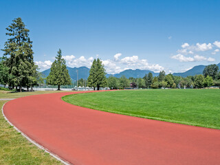 Red jogging track of recreational stadium on bright sunny day