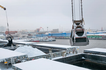 Autumn bad weather, snow, loading coal into the holds of industrial ships in the seaport