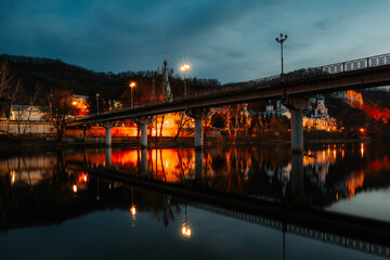 Fototapeta na wymiar Bridge over the Seversky Donets river in Svyatogorsk against the background of an Orthodox monastery in the evening