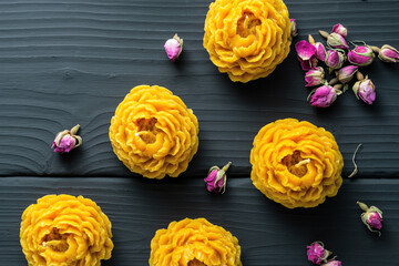 Decorative flower candles made of beeswax with a honey aroma for interior and tradition on the dark wooden background.