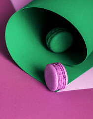 French macaroons on a multi-colored paper background with place for text. Pastry chef app with copy space. Creative concept.