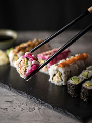 healthy vegan sushi rolls with chopsticks. Black chopsticks, dark background.