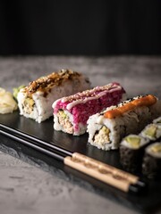 healthy vegan sushi rolls with chopsticks. Black chopsticks, dark background.