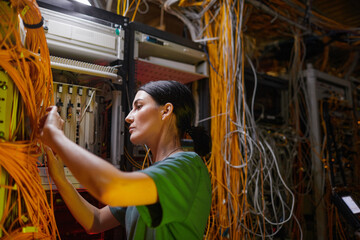 Side view at young woman wearing military uniform inspecting server while working in server room, copy space