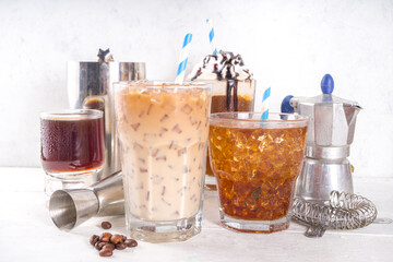 Set with different iced summer coffee drinks - espresso, frappe, latte, cappuccino, with whipped cream, syrup and crushed ice, in various glasses and mugs on white background copy space