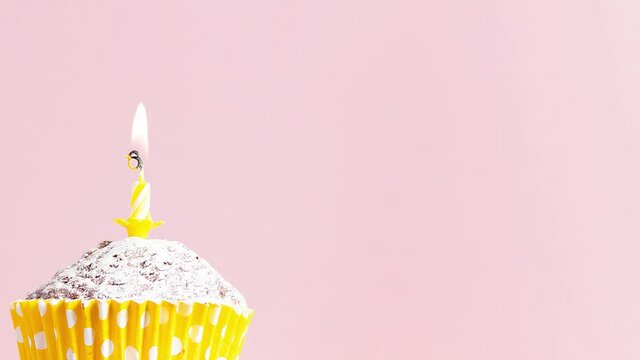 Video 4k festive homemade cupcake with yellow birthday candle moves over pink background copy space for text