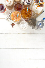 Set with different iced summer coffee drinks - espresso, frappe, latte, cappuccino, with whipped cream, syrup and crushed ice, in various glasses and mugs on white background copy space