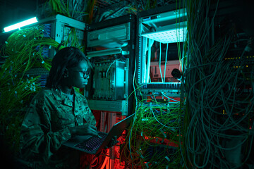 Side view portrait of young African-American woman wearing military uniform inspecting server while...