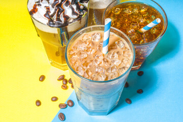 Set with different iced summer coffee drinks - espresso, frappe, latte, cappuccino, with whipped cream, syrup and crushed ice, in various glasses and mugs on trendy bright yellow blue background