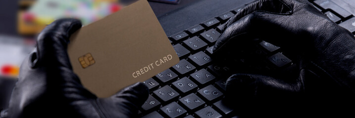 Internet Theft - Thief's Gloved Hands With Credit Card Behind Laptop