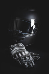 Black leather motorcycle gloves and helmet on black background.