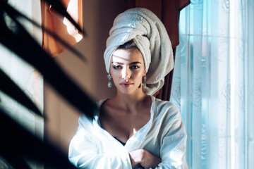 Beauty woman with towel on head relaxing, after spa or morning shower. Woman in bathrobe after wellness and skin care procedures. Rest, wellness and and care concept.