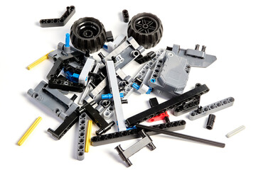 Plastic parts of the constructor, connecting elements and wheels for assembling movable models on a white background, floating focus.