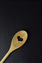 Wooden spoon on slate stone background, in dark color. Copy space.