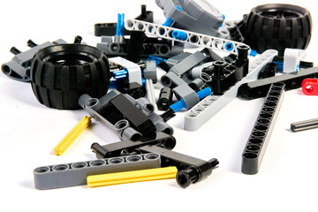 Plastic parts of the constructor, connecting elements and wheels for assembling movable models on a white background, floating focus.