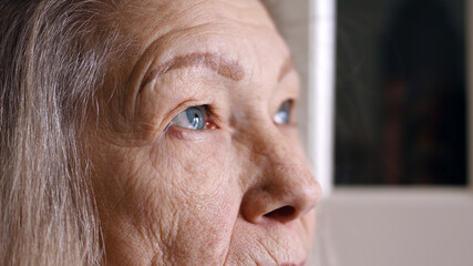 Close up portrait of sad senior woman with blue eyes gray hair and wrinkled skin. High quality photo