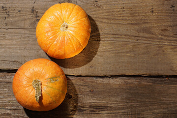 Harvest of two small pumpkins on a wooden table
